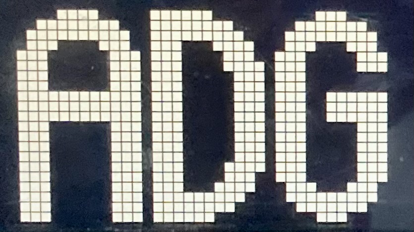 A White dot matrix with the initials "ADG"